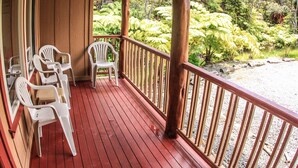 A wooden deck with red flooring and white plastic chairs. - Cute, spacious rainforest cottage close to HVNP (Volcano)