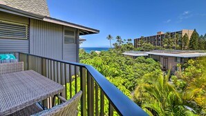 A balcony with wicker furniture overlooking a lush garden and a view of the ocean. - Gorgeous Oceanfront Kihei Condo w/ Balcony! (Kihei)