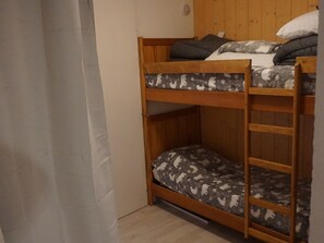 A bunk bed with a lower bunk and a ladder, a wooden headboard, and a patterned bedspread. - Studio cabin for 4 in Orcières Merlette (Orcières Merlette)