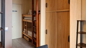Ein Zimmer mit einem Etagenbett, einem Holzschrank und einem kleinen Tisch.