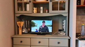 Eine Küche mit einem Fernseher auf einem Schrank, Holdekochern und einem Herd.