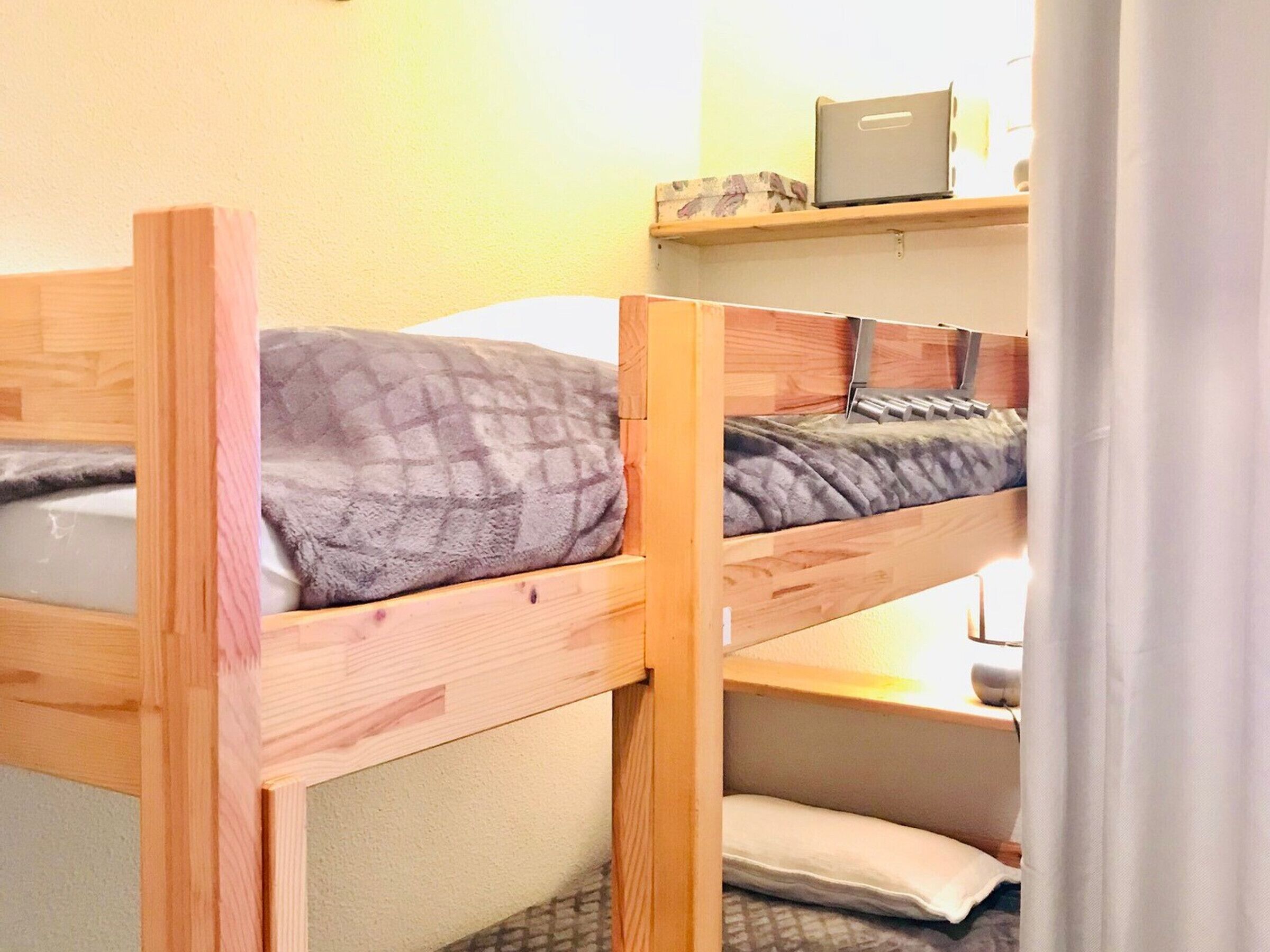 Two bunk beds with wooden frames and gray bedding.