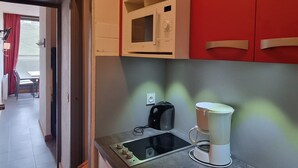 A kitchen with a microwave, coffee maker, and a small sink.