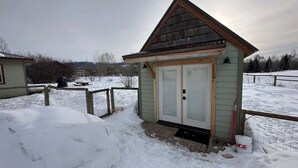 Ein kleines Holzgebäude mit geneigtem Dach, einer Tür und einem Fenster.
