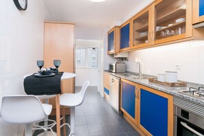 Enjoy meals in this cozy kitchen with a microwave and stainless steel oven, adjacent to a dining area with a small table and two chairs.