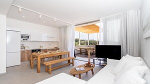 Ein modernes Wohnzimmer mit einer Couch, einem Holzes Esstisch und einem Fernseher.