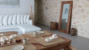 Ein modernes Wohnzimmer mit Steinwand, Holztisch, weißem Sofa und einem großen Spiegel.