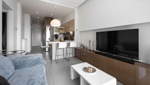 A modern living room with a large flat-screen TV, a sofa, and a coffee table. - Awesome Sea View Nilie Hospitality MGMT (Thessaloniki)