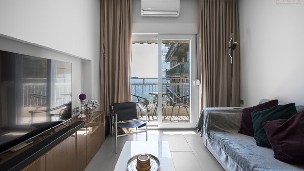A modern hotel room with a balcony, a sofa, a TV, and a dining area. - Awesome Sea View Nilie Hospitality MGMT (Thessaloniki)