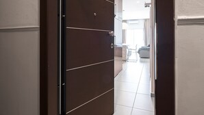 A hallway with a brown door leading to a room with a white ceiling and a visible window. - Awesome Sea View Nilie Hospitality MGMT (Thessaloniki)