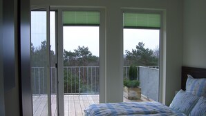 Ein Schlafzimmer mit Bett, einem Balkon und Blick auf Bäume.