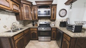 Una cocina con armarios de madera, estufa de acero inoxidable, microondas y cafetera.