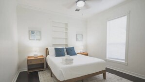 Un dormitorio con cama, mesitas de noche, una ventana y una estantería empotrada.