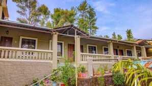 A row of two-story buildings with balconies, stone walls, and potted plants. - Hirkani Garden & Resort (Mahabaleshwar)