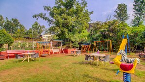 A playground with swings, slides, and a zebra play structure. - Hirkani Garden & Resort (Mahabaleshwar)
