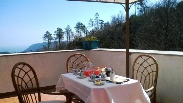 Une table dressée pour deux personnes, avec vue sur la mer et les arbres en arrière-plan.