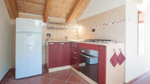 Une cuisine de taille réduite, équipée d’un réfrigérateur, d’une cuisinière et de placards.