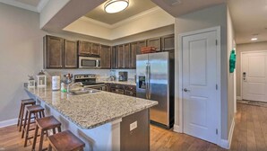 A modern kitchen with granite countertops, stainless steel appliances, and wooden cabinets. - Private Balcony! Free Activities! Walk to Beach! Gated Community Alerio B205 (Destin)