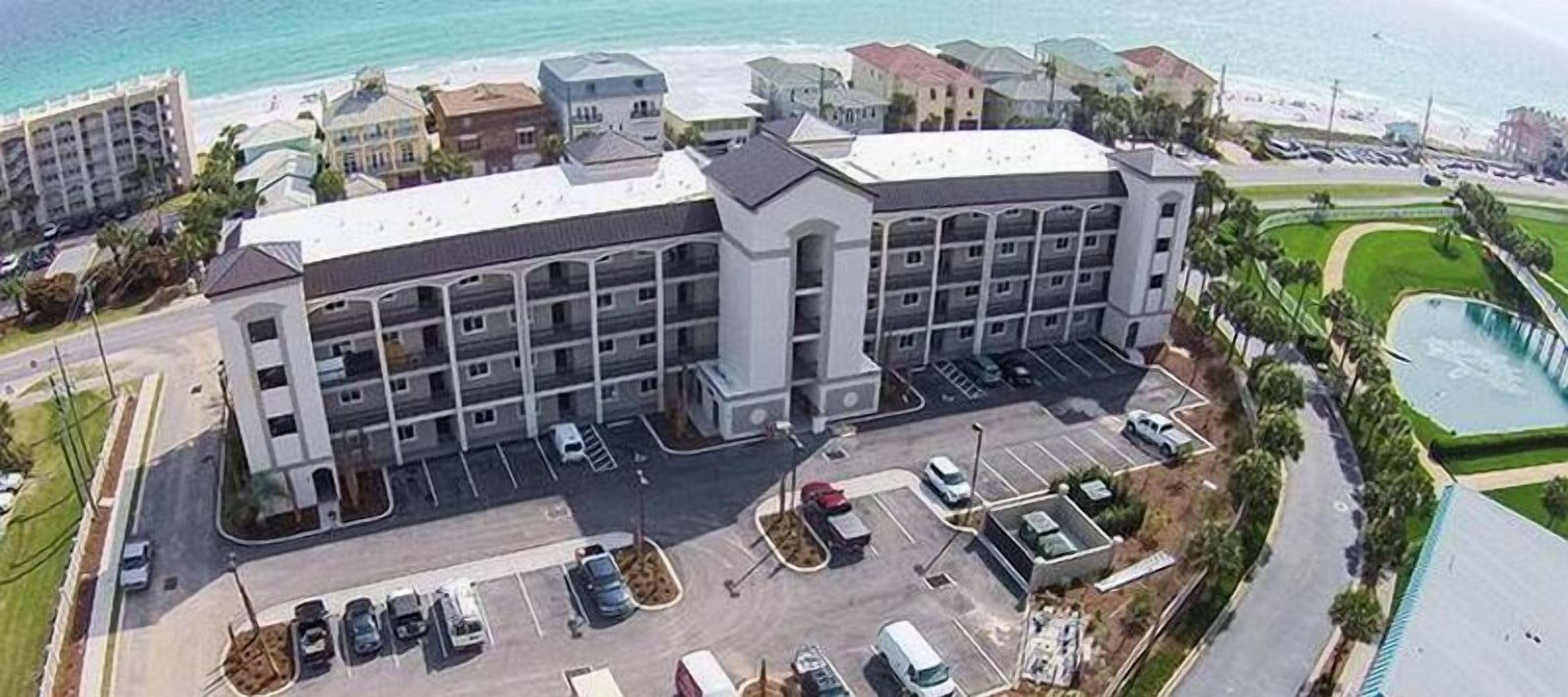 Un hotel de varios pisos con un patio central, aparcamiento y zona de piscina.