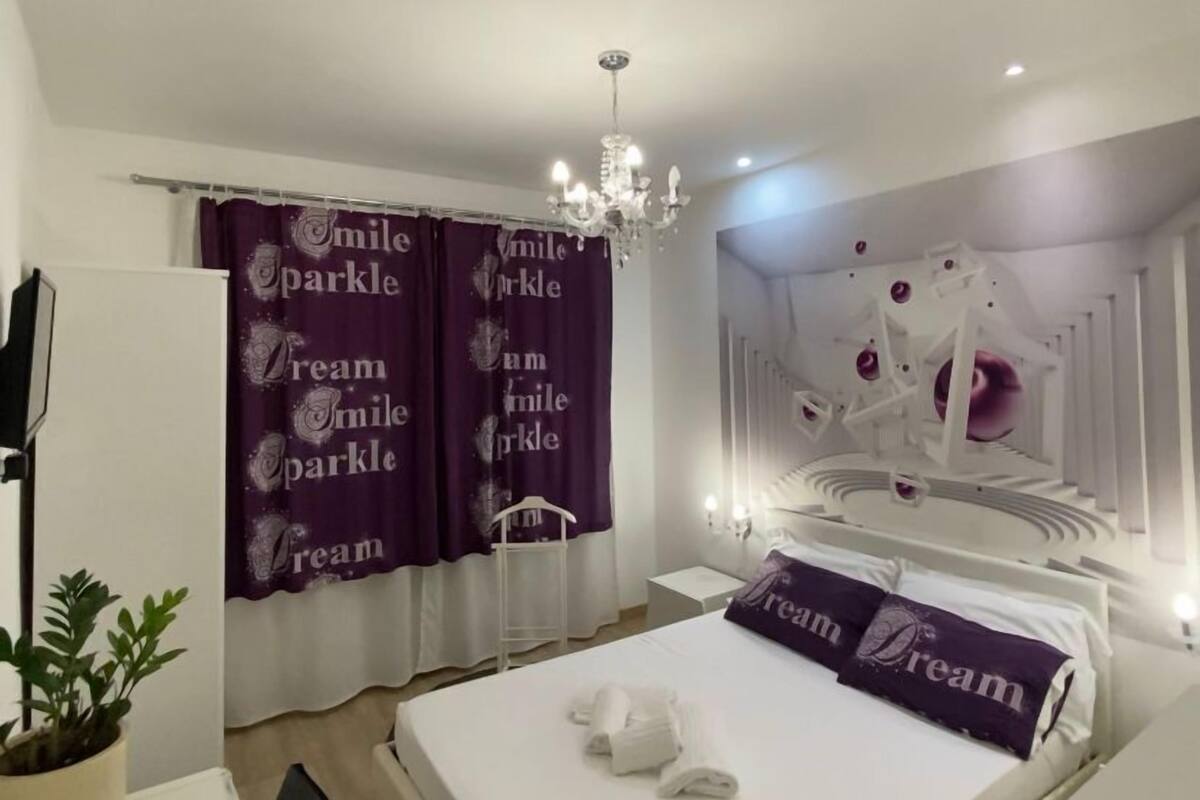 A modern bedroom with a bed, a desk, and a chandelier.
