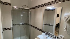 Une salle de bain moderne avec une douche à parois de verre, un lavabo blanc et un sèche-cheveux fixé au mur.