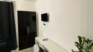 Une pièce moderne et minimaliste, avec un bureau blanc, une chaise noire et une plante en pot.