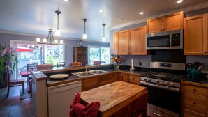 A modern kitchen with wooden cabinets, stainless steel appliances, and pendant lighting. - Lovely, Spacious Villa with HotTub, Outdoor Dining, Fire Pit (Volcano)