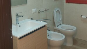 Kylpyhuoneessa on pesuallas, kaksi wc-istuinta, peili ja punaisella kehyksellä varustettu ikkuna.