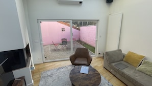 Un saló modern amb un gran finestral corredís que dona a un pati de maó rosa.