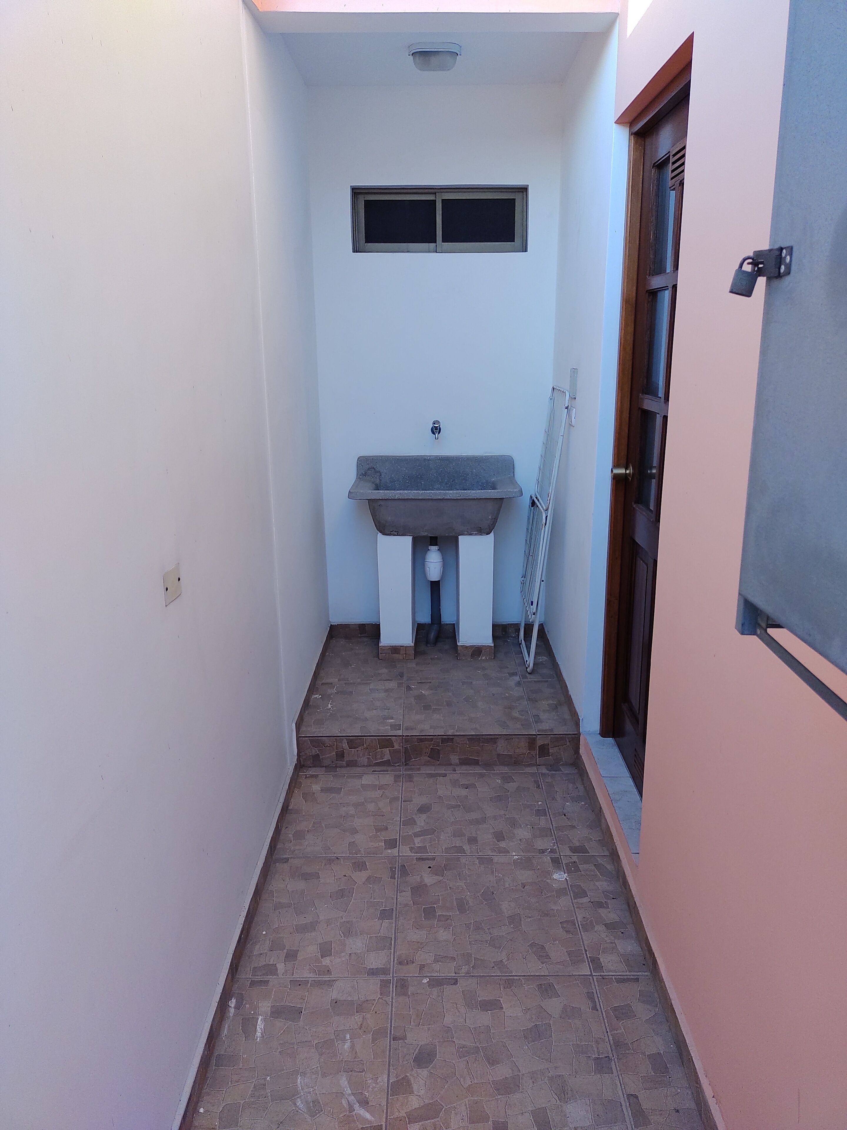 A narrow bathroom with a sink, a window, and a door.