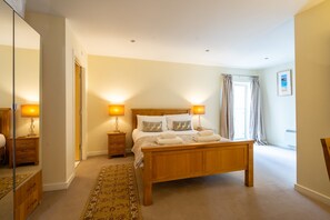 Relax in this serene bedroom with a large bed, two bedside tables, and a spacious mirror.