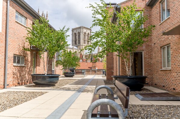 Stroll through the serene courtyard, surrounded by lush greenery and historic brick buildings.