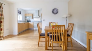 Une cuisine moderne avec des meubles en bois et un coin repas comprenant une table et des chaises en bois.