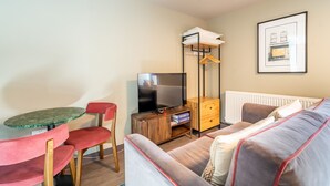 A modern living room with a sofa, a TV, a small table, and a red chair. - The Falcon Apartment 6 (York)