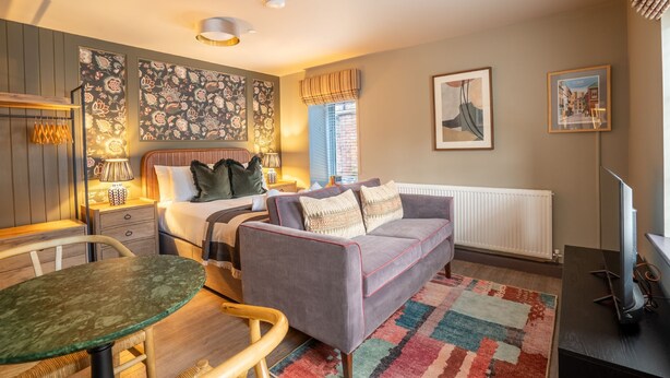 A cozy bedroom with a bed, a sofa, a dining table, and a TV. - The Falcon Apartment 7 (York)