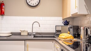 A modern kitchen with a sink, a toaster, a kettle, and a loaf of bread on the counter. - The Falcon Apartment 7 (York)