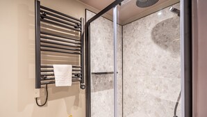 A modern bathroom with a glass-enclosed shower, a towel rack with a towel, and a gold door handle. - The Falcon Tap Apartment 2 (York)