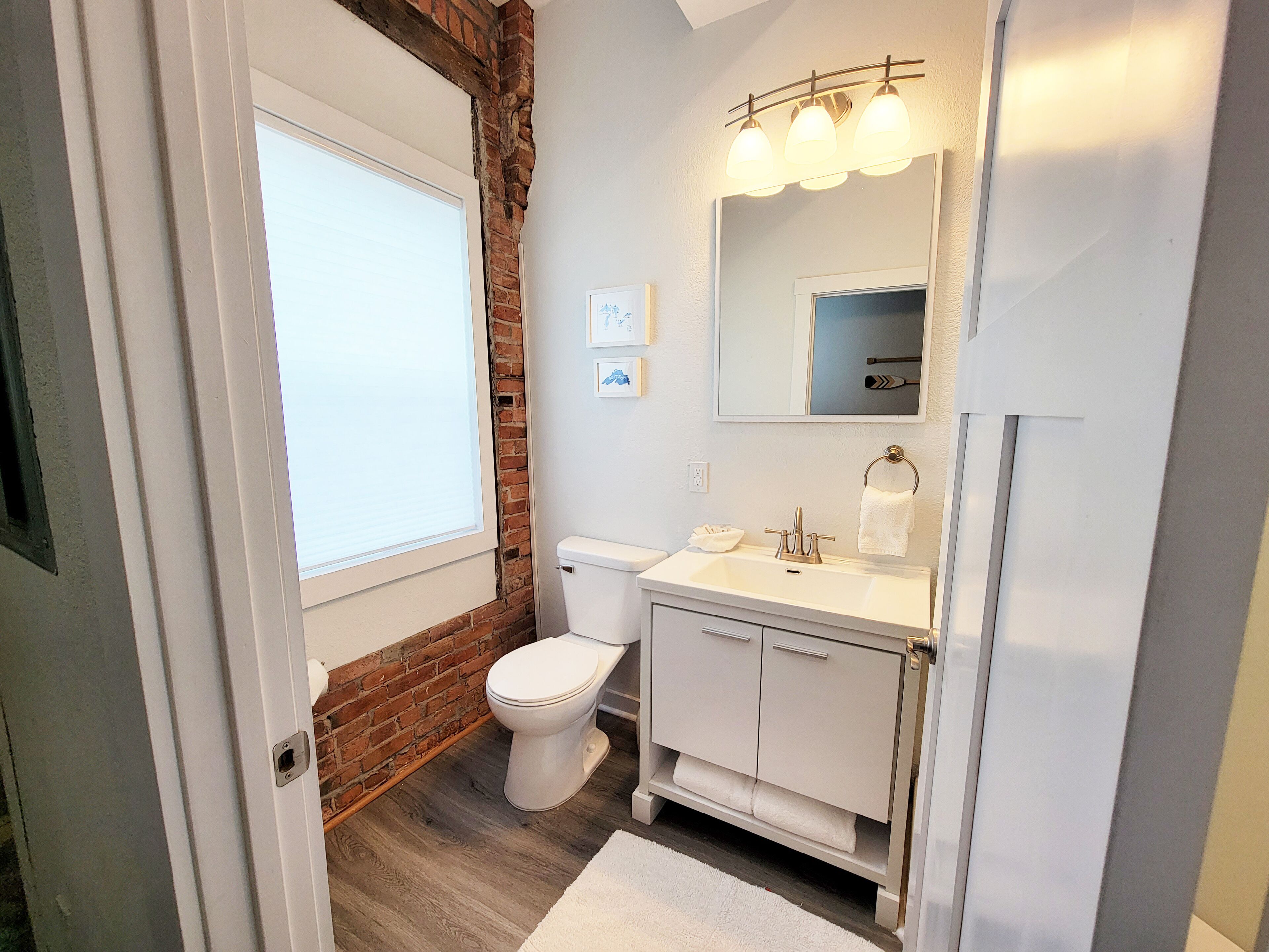 Een badkamer met een wit toilet, een wastafel met spiegel en een raam.