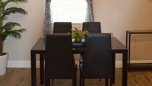 Un espace repas comprenant une table, des chaises, une plante en pot et un luminaire décoratif.