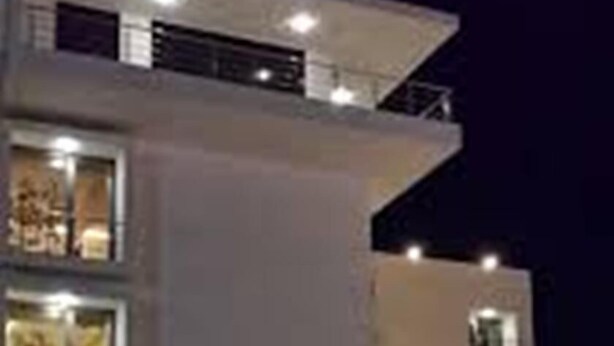A modern multi-story building with illuminated windows and a well-lit entrance. - KRSNA Lila By The Blues Hotels (Sanand)