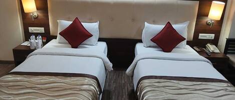 Habitación de hotel con dos camas, cabeceros, lámparas de noche, mesitas de noche y teléfono en la pared.