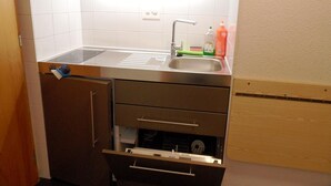 A compact kitchen with a sink, cabinets, and a wooden countertop.