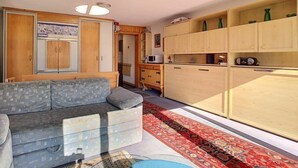 A compact living space with a sofa, a kitchenette, and wooden cabinets.