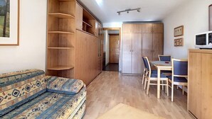 A compact living space with a sofa, a dining table with chairs, a kitchenette, and a wardrobe. - Studio *** - 6th floor - close to the centre, shops and bus stop - sunny balcony with very nice view (Verbier)