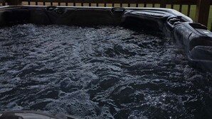Un bain à remous avec une terrasse en bois et une vue sur les montagnes.
