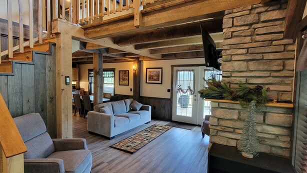 Un vaste espace de vie agrémenté d’une cheminée en pierre, d’un escalier en bois et d’un coin salon confortable.