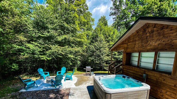 Een houten hut met een hottub, zitplaatsen buiten en een terras.