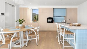 Una cocina moderna con armarios blancos, horno empotrado y salpicadero azul.