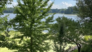 A serene lakeside view with a grassy area, trees, and a stone pathway.