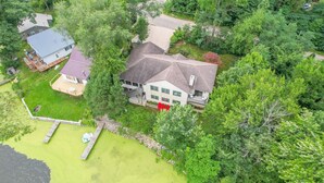 A large house with a spacious front yard, a covered patio, and a small pond.